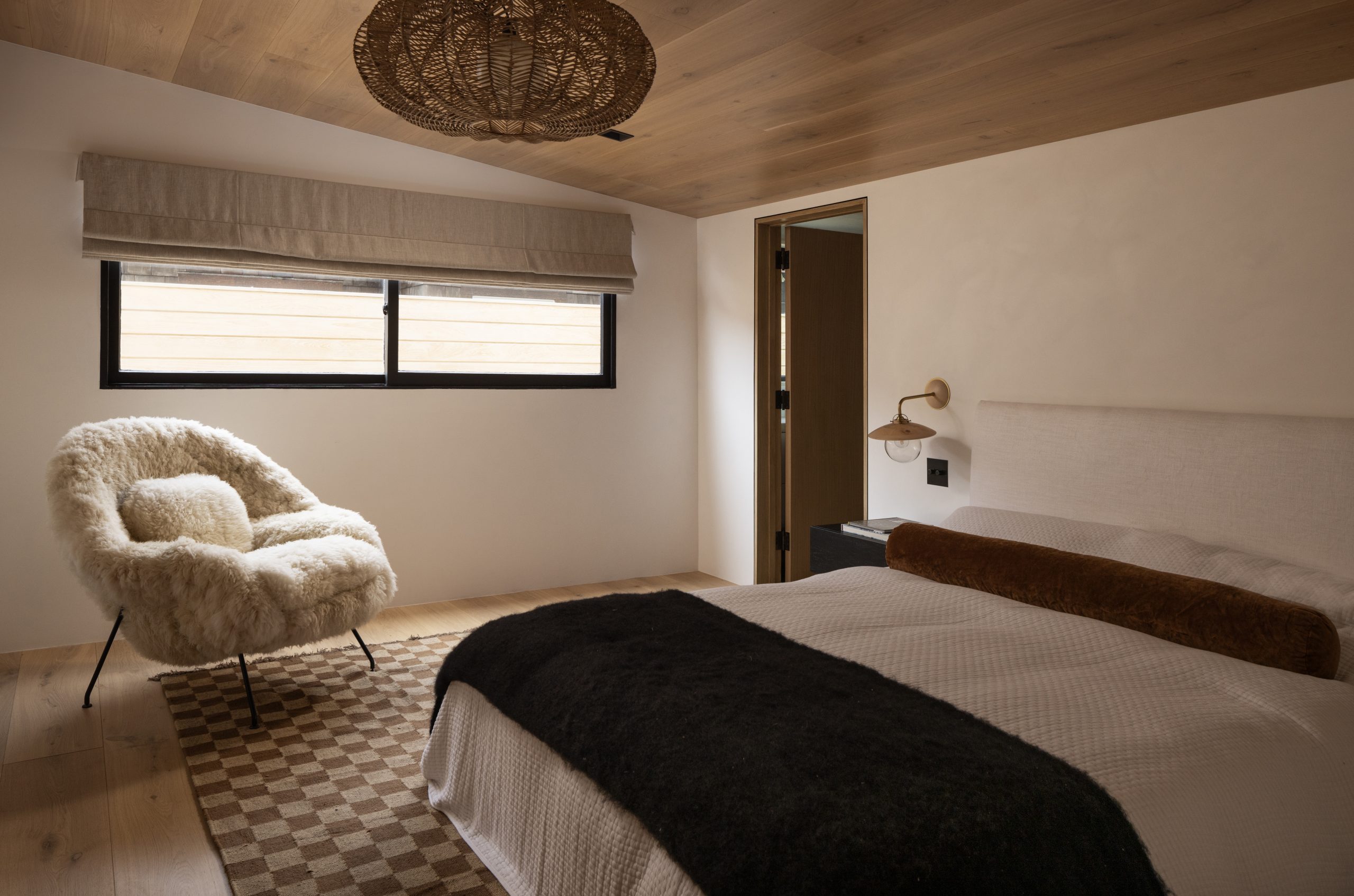 A cozy bedroom, featuring a wood-clad ceiling. 