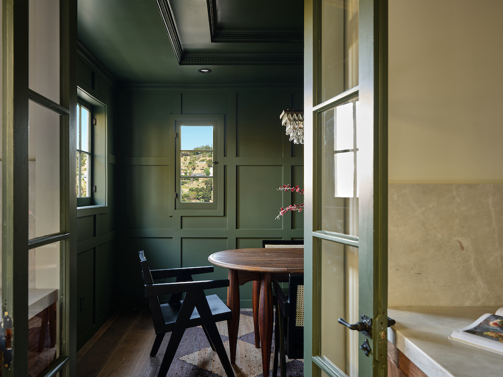 Moody green dining room with French doors and wall panels.
